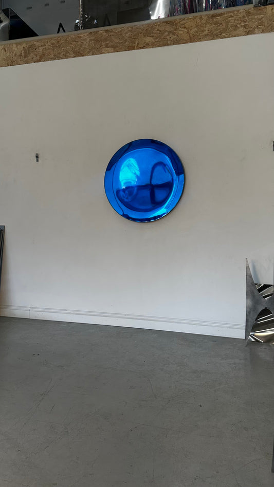 Piers Henry Interiors blue circular concave metal wall mirror with a polished reflective surface on a white wall